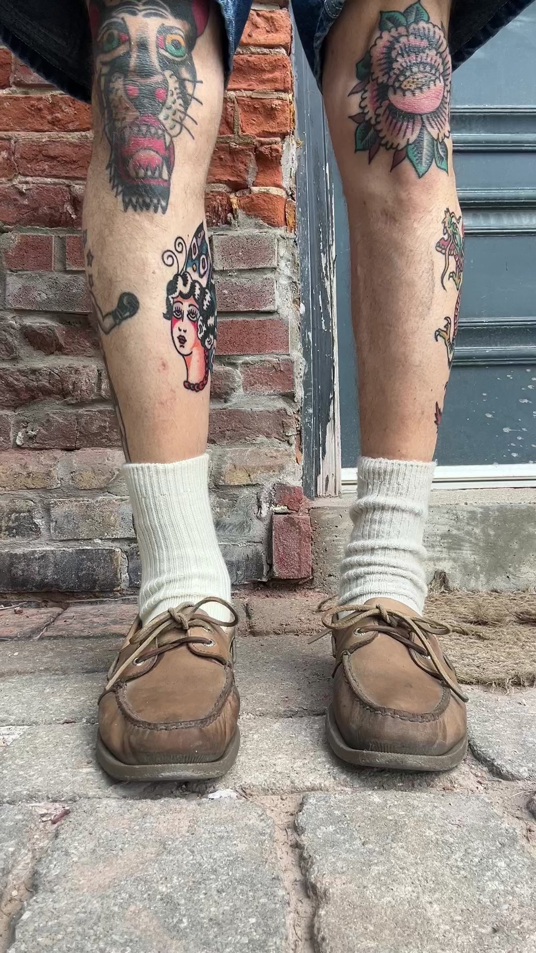 Man's legs with tattoos wearing natural socks and boat shoe