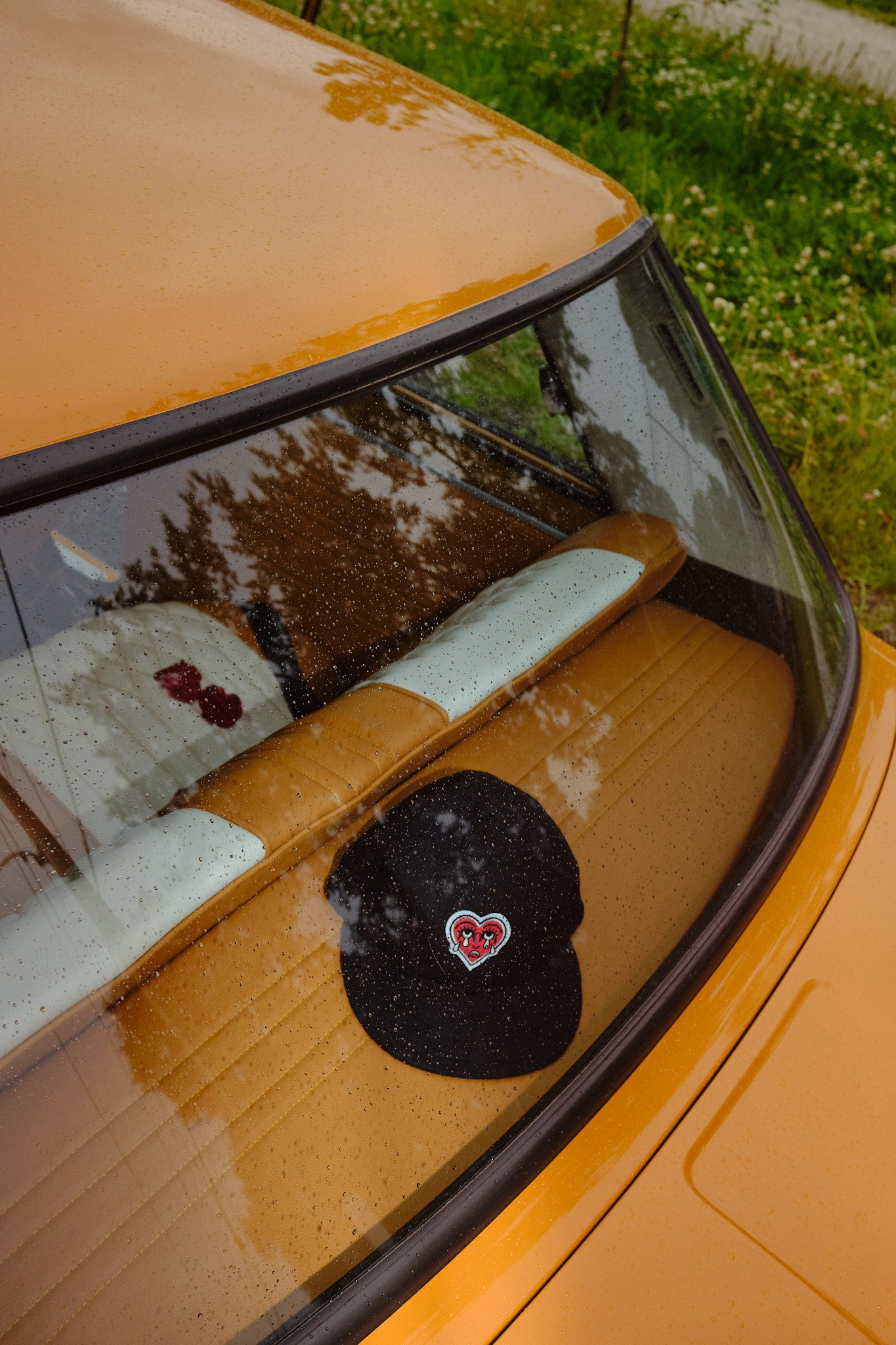 Black cap with a red crying heart patch in a car window