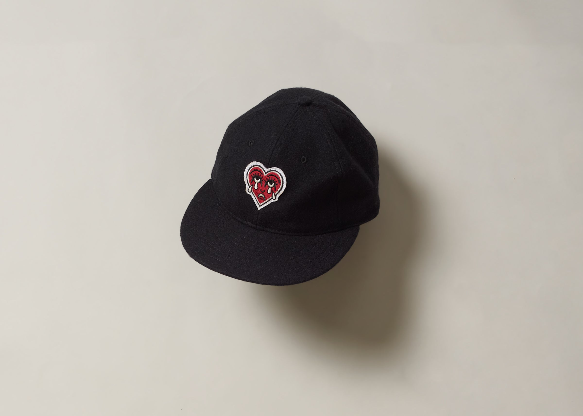 Black cap with a red crying heart logo