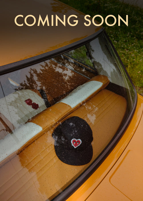 Cap with red crying heart logo in the back window of a car.