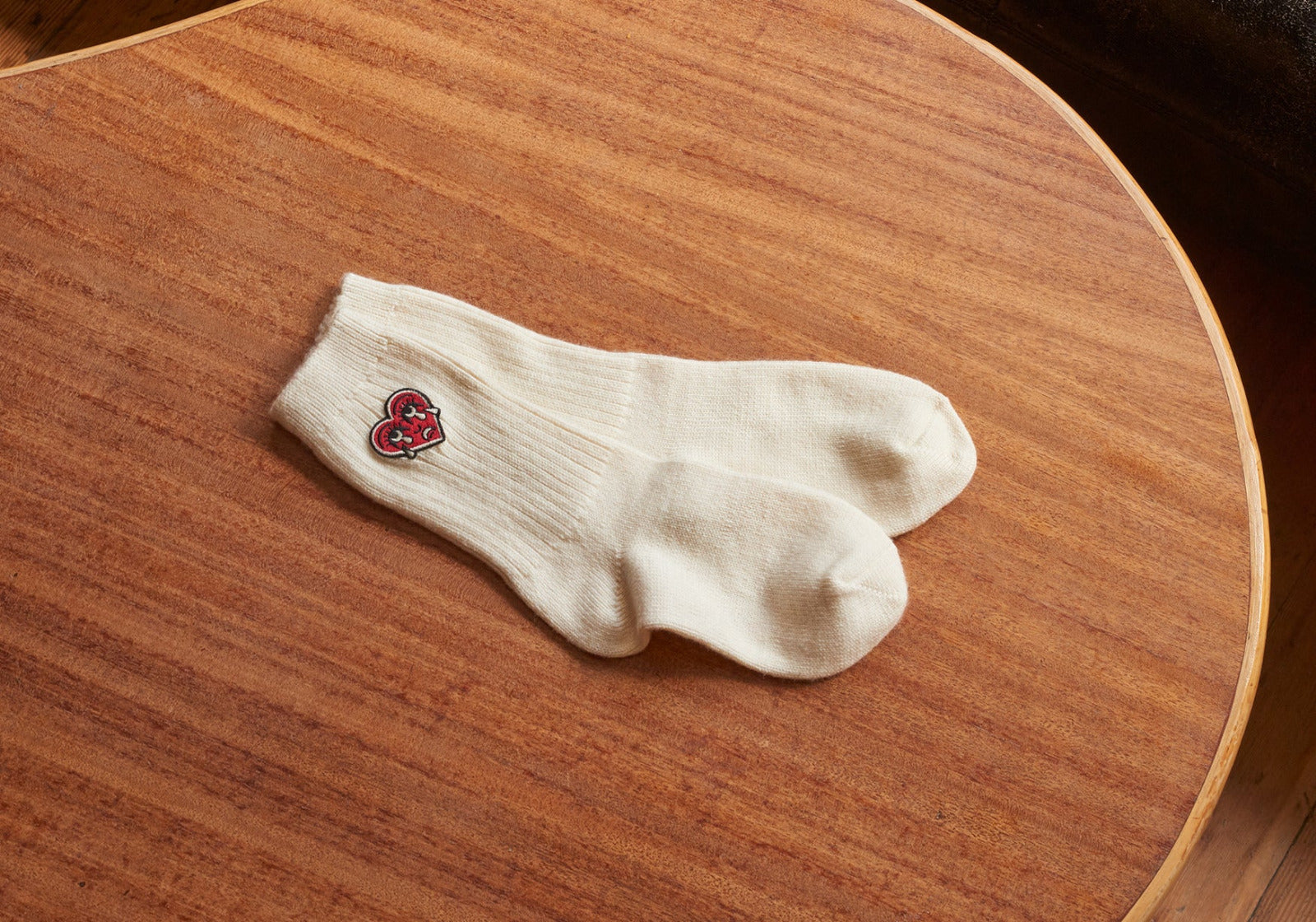 White sock with a red crying heart logo on a wooden surface